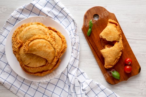 Preview: Homemade Deep Fried Italian Panzerotti Calzone with sauce on a white wooden background, top view.