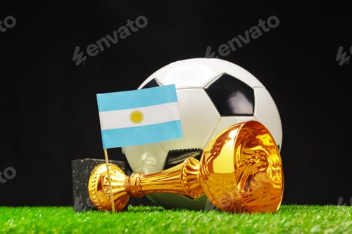 Preview: Argentina soccer trophy and flag displayed with a black and white ball on green grass