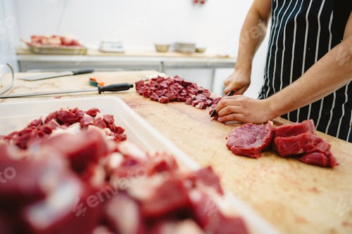 Preview: Butcher cutting slices of raw meat on wooden board