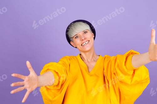 Preview: Stylish european woman on purple background looking at the camera smiling with open arms for hug