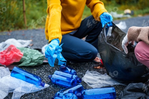 Preview: Close-up of young women girls hands sorting recyclable plastic bottles into trash bags outdoors