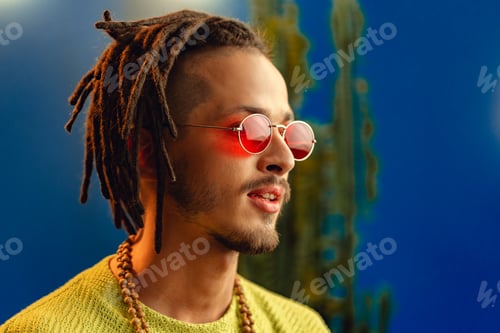 Preview: Portrait of a positive handsome caucasian guy with dreadlocks against blue background