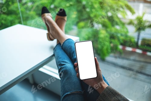 Preview: Mockup image of a woman holding mobile phone with blank white desktop screen while sitting in office
