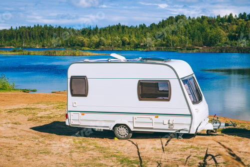 Preview: A Peaceful Lakeside Camping Scene Featuring a Charming White Caravan by the Water's Edge