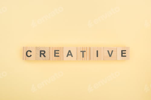 Preview: top view of creative lettering made of wooden cubes on yellow background