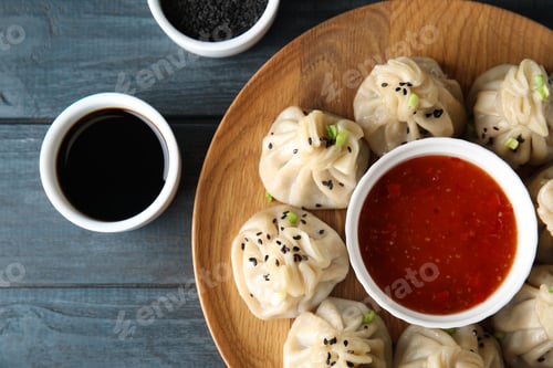 Preview: Tasty baozi dumplings served with sesame seeds and sauces on wooden table, top view