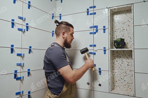 Preview: Tiler knocks the wedges of the ceramic tile leveling system off the wall in the bathroom