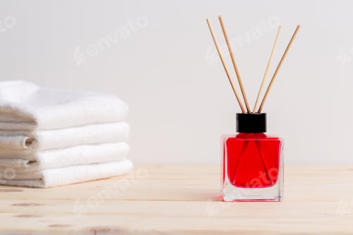Preview: Bright red fragrance diffuser with bamboo sticks near folded towels in a modern setting