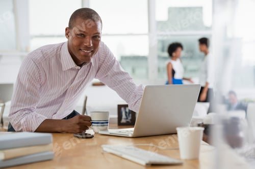 Preview: A business environment, an office workplace. A young man using a laptop computer on a desk.