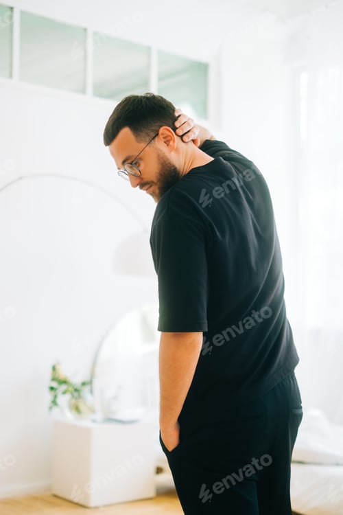 Preview: Portrait of stylish caucasian man in eyeglasses and black t shirt in bright living room.