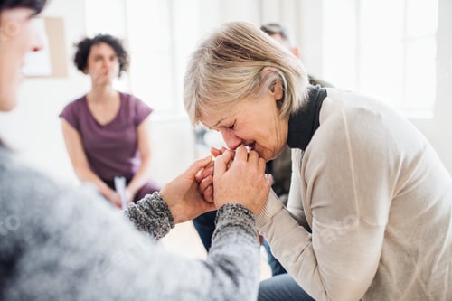 Preview: A senior depressed woman crying during group therapy.