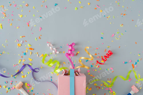 Preview: Creative composition made with gift box and party streamers on pastel grey background.