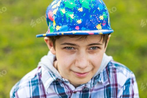 Preview: Portrait of a teenager boy in a baseball cap against the background of a meadow with green grass