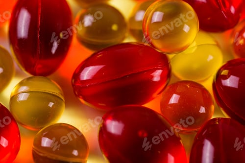 Preview: yellow and red medical capsules on a mirror surface