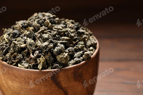 Preview: Bowl of Tie Guan Yin oolong tea leaves on wooden background, closeup. Space for text