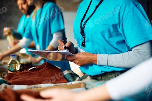 Preview: Volunteer taking notes while organizing distribution of donations at humanitarian aid center.