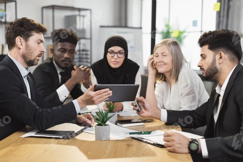 Preview: Multi ethnic group of business people using tablet at office