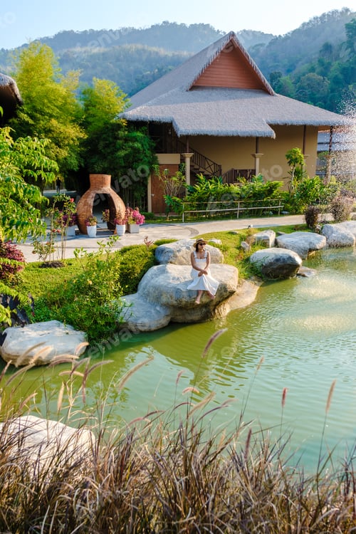 Preview: Asian women relaxing by a water pond in Khao Yai Thailand at sunset