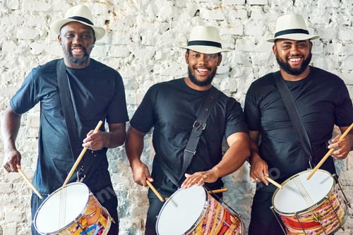 Preview: Cropped portrait of a group of handsome young male drummers playing at Carnival