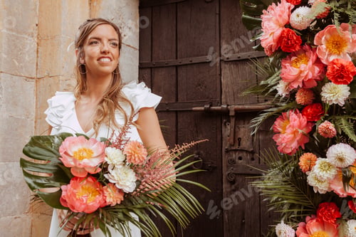 Preview: Cheerful wedding bride posing with a bouquet of flowers outdoors