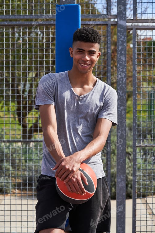 Preview: Smiling Hispanic sportsman with ball on street