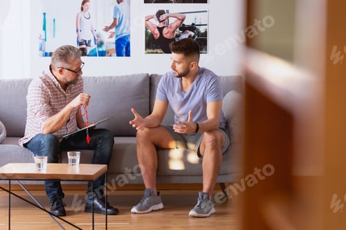 Trainer Consults with Young Adult on Gray Sofa