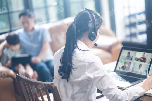 Preview: Asian business woman talking to colleague team about plan in video conference with family behind