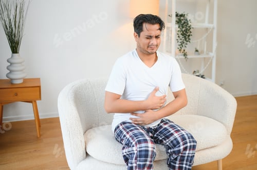 Preview: Sad exhausted guy of indian and arabian ethnicity, holds his hands on his stomach