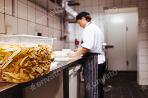 Preview: Close-up of potato chips soaked in water with chef working in background