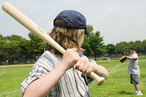 Preview: Young player ready at bat in a sunny baseball game with a teammate