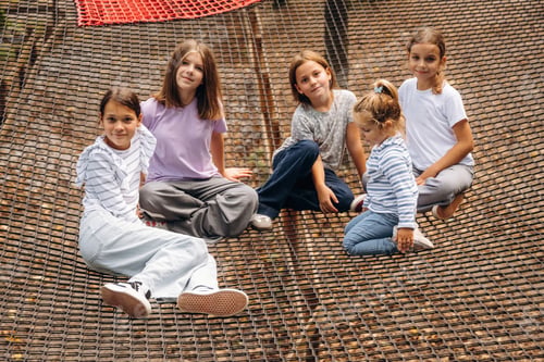 Preview: In casual clothes, relaxed, sitting. Kids are playing on the children's amusement ropes course