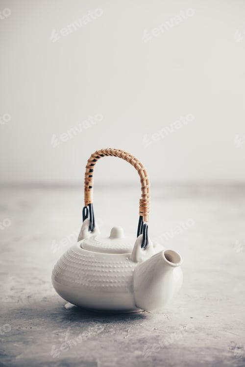 Preview: White teapot on rustic stone table against the white wall