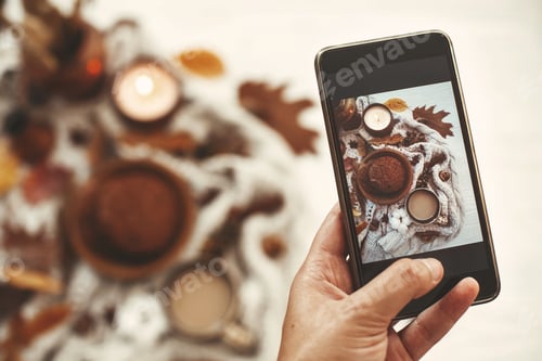 Preview: Hand holding phone and taking photo of stylish autumn flat lay