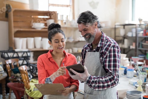Preview: Male and female potter discussing over tablet pc