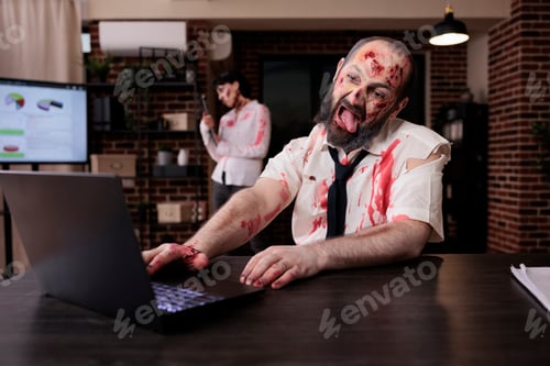 Preview: Creepy scary zombie using laptop at desk