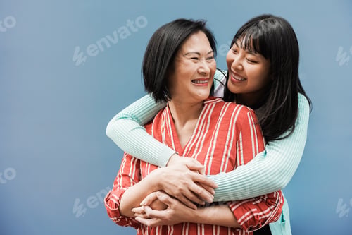 Preview: Asian mother and daughter having fun outdoor with blue background - Main focus on mother face
