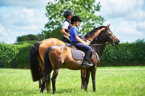 Preview: Side view of mature woman and girl horseback riding, looking away