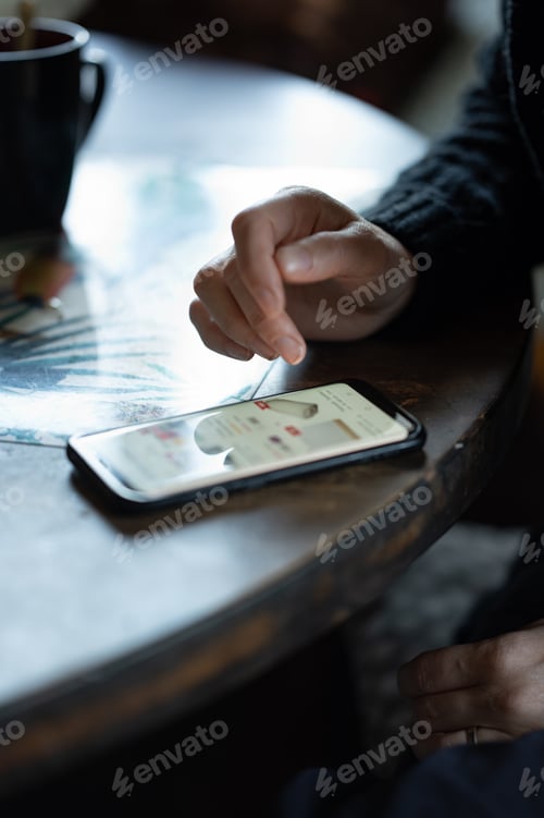 Preview: Closeup photo of a woman checking her phone on a wooden table