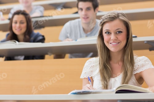 Preview: Students Sitting At The Lecture Hall While Smiling And Taking Notes