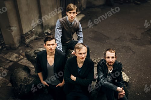 Preview: stylish handsome group of men standing and posing on the background of city street