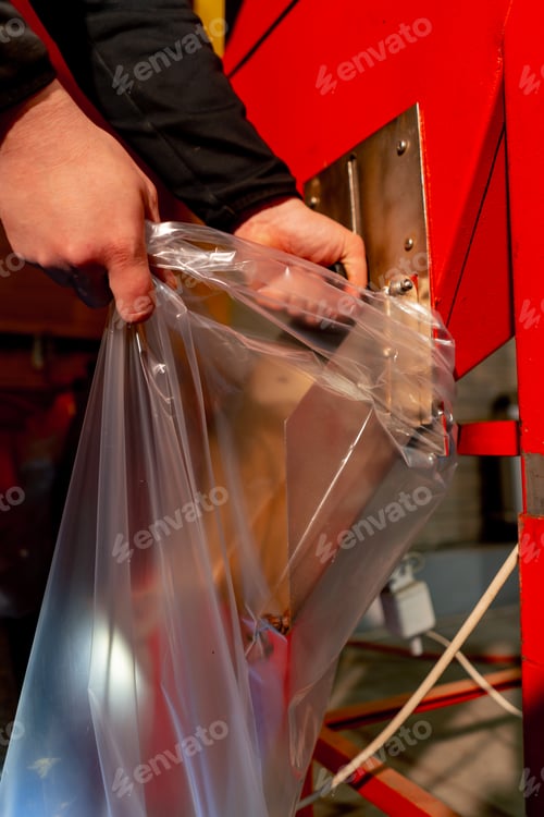 Preview: close up at a roasting factory worker pours coffee into a large transparent bag for shipment