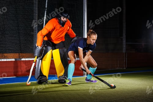 Preview: Female field hockey player attacking the goalie to score a goal