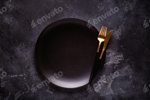 Preview: Clean empty black plate with cutlery.