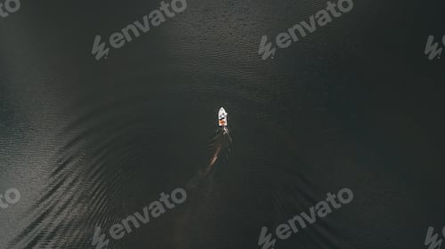 Preview: Drone view of a boat sailing across the dark water of the lake.