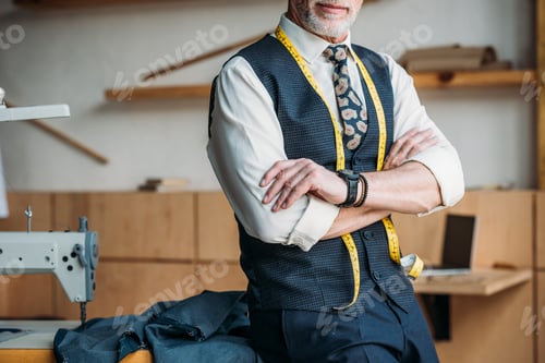 Preview: cropped image of tailor standing with crossed arms at sewing workshop