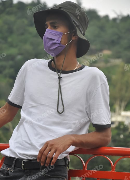 Young Adult Outdoors Leaning On Railing Wearing Mask