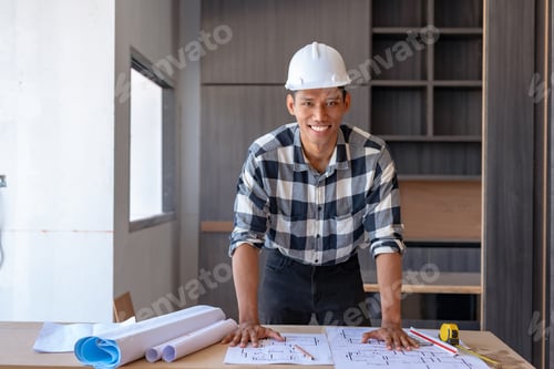Preview: Cheerful young asian man architect reviews building plans on a construction site