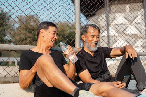Preview: Two senior men enjoying wellness, laughter, and hydration during a break at the park