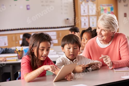 Preview: Senior teacher helping elementary school pupils using tablet