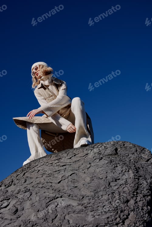 Preview: woman in autumn clothes stands on a rock landscape blue sky lifestyle